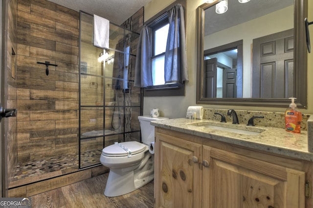 bathroom featuring tiled shower, toilet, a textured ceiling, vanity, and hardwood / wood-style flooring