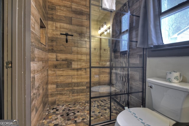 bathroom with a tile shower and toilet