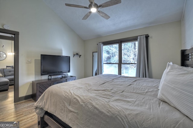 bedroom featuring lofted ceiling, a textured ceiling, ceiling fan, and light hardwood / wood-style floors