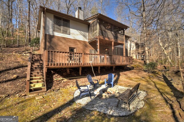 rear view of house with a wooden deck, an outdoor fire pit, and a sunroom