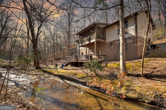 view of property exterior featuring a deck with water view and a sunroom