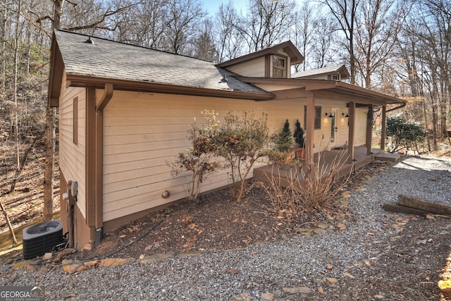 view of side of property with a porch and central AC