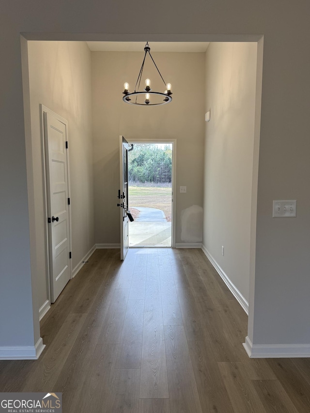 foyer entrance featuring a notable chandelier, dark wood-style floors, and baseboards