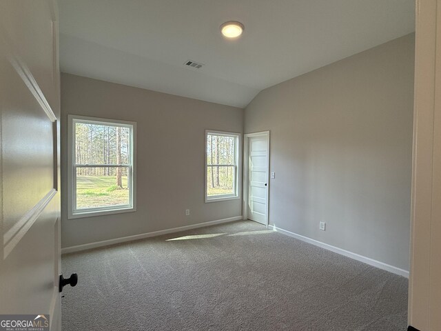 unfurnished room with baseboards, visible vents, carpet flooring, and vaulted ceiling