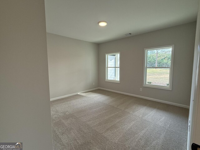 carpeted spare room with baseboards and visible vents