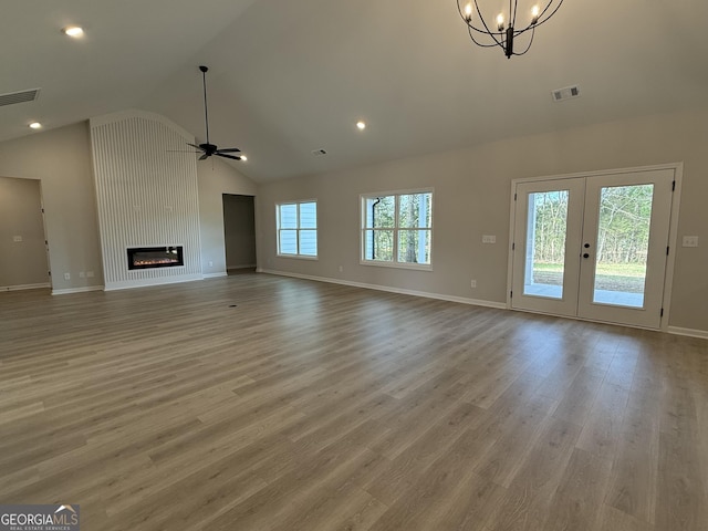 unfurnished living room with ceiling fan with notable chandelier, visible vents, and a wealth of natural light