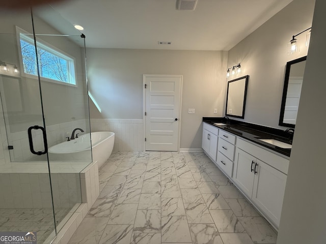 full bathroom with marble finish floor, a sink, a stall shower, a freestanding bath, and double vanity