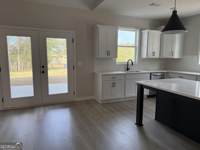 kitchen with visible vents, a sink, light wood-style floors, and tasteful backsplash