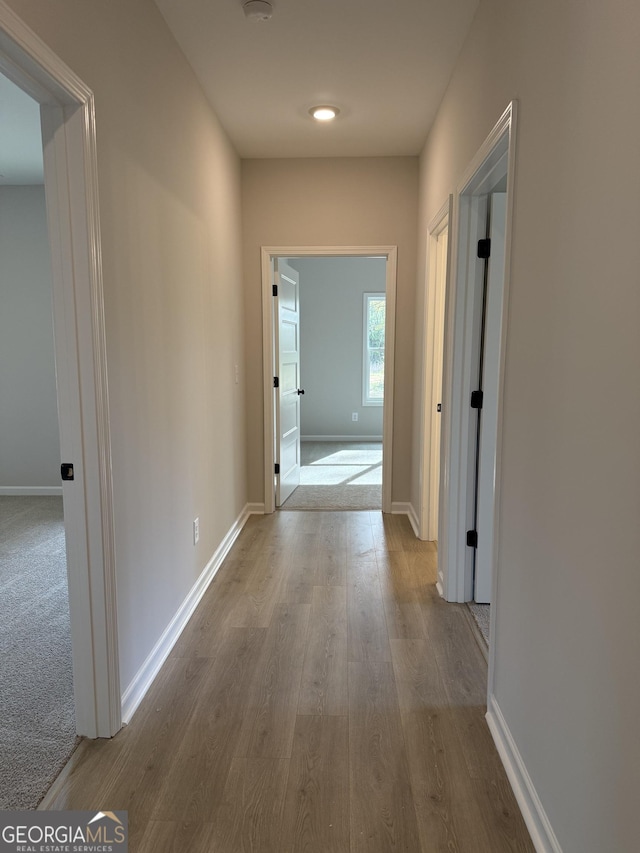 hall with baseboards and wood finished floors