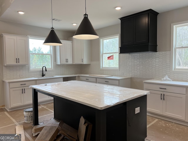 kitchen featuring visible vents, backsplash, a sink, and decorative light fixtures