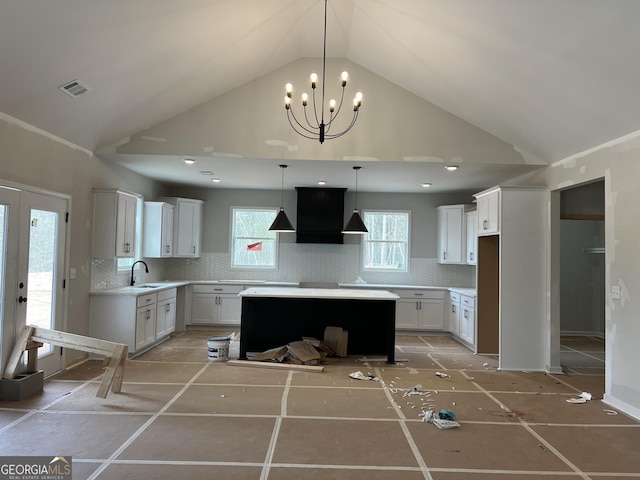 kitchen featuring light countertops, decorative backsplash, white cabinets, a sink, and premium range hood