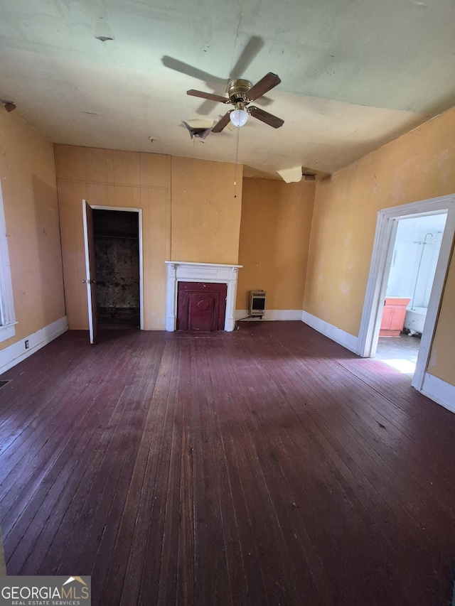 unfurnished living room with heating unit, dark wood-type flooring, and ceiling fan