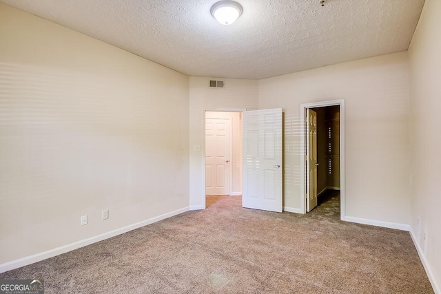 unfurnished bedroom featuring carpet, a walk in closet, visible vents, and baseboards