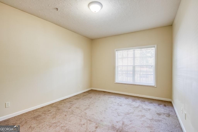 carpeted empty room featuring baseboards and a textured ceiling