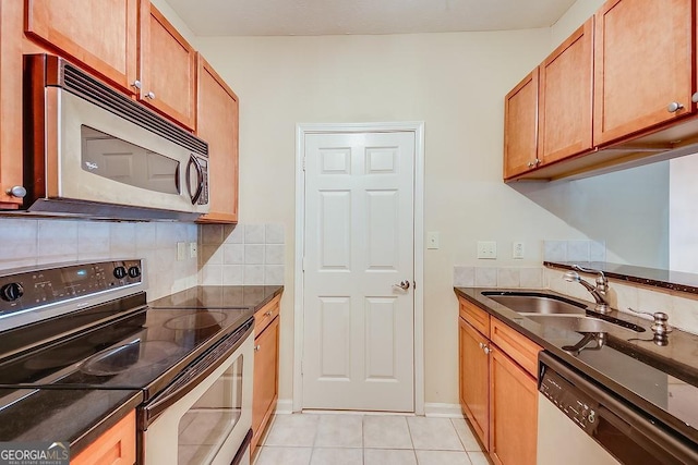 kitchen with light tile patterned floors, tasteful backsplash, dark stone countertops, stainless steel appliances, and a sink