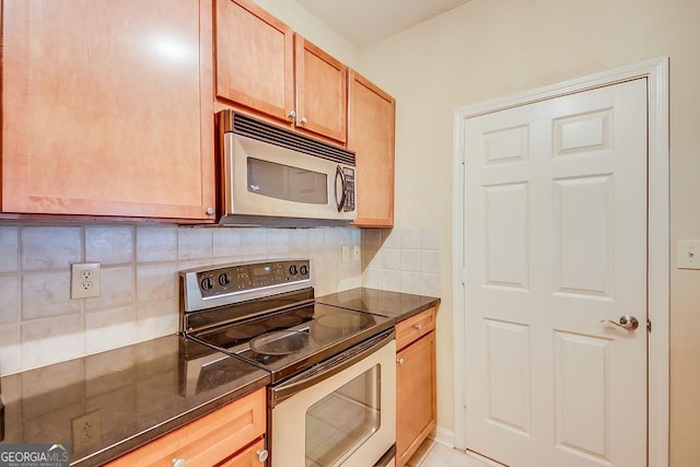 kitchen featuring stainless steel appliances, dark stone counters, and tasteful backsplash