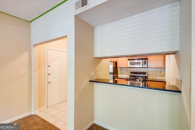 kitchen with stainless steel appliances, dark countertops, visible vents, and decorative backsplash