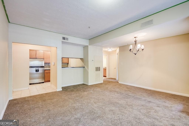 unfurnished living room featuring baseboards, visible vents, a notable chandelier, and light colored carpet