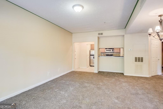 unfurnished living room with carpet floors, visible vents, and an inviting chandelier