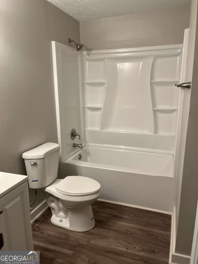 full bathroom featuring hardwood / wood-style flooring, vanity, a textured ceiling, and toilet