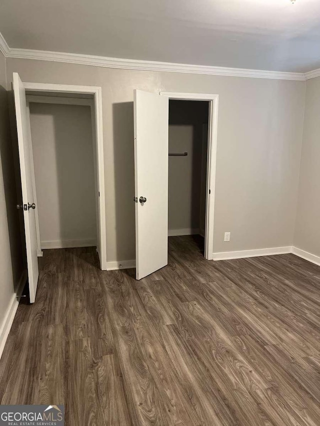 unfurnished bedroom with ornamental molding, dark wood-type flooring, and a closet