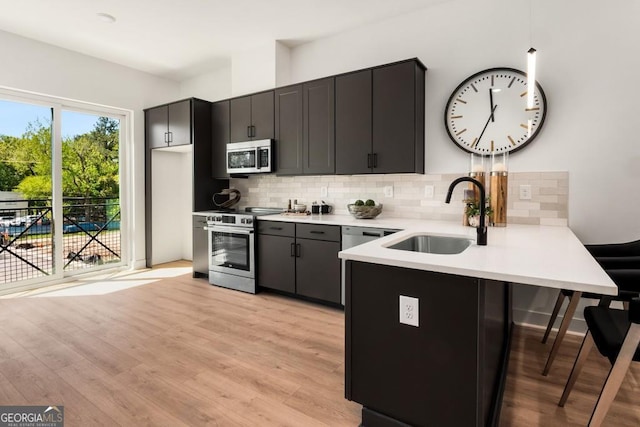 kitchen featuring sink, a breakfast bar area, stainless steel appliances, decorative backsplash, and kitchen peninsula