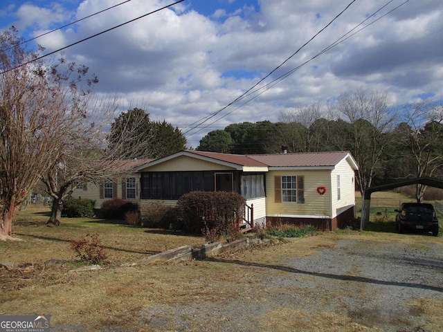 view of front of house with a carport, a sunroom, and a front yard