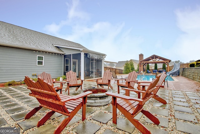 view of patio / terrace with a fenced in pool, a gazebo, a sunroom, and a fire pit