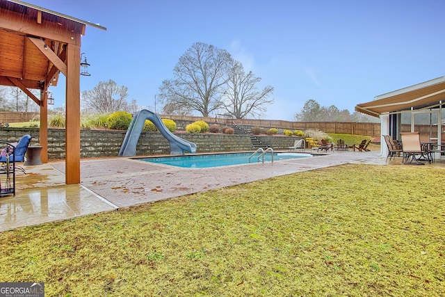 view of pool with a patio area, a lawn, and a water slide