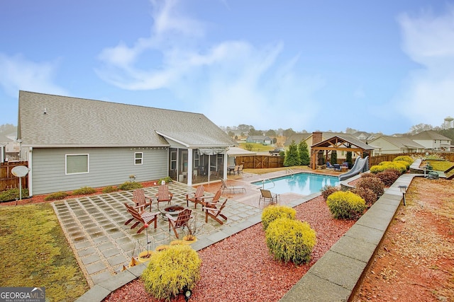 view of pool featuring a gazebo, a water slide, a patio area, and a sunroom