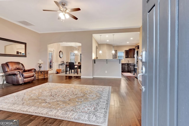 living room featuring crown molding, ceiling fan, and dark hardwood / wood-style flooring