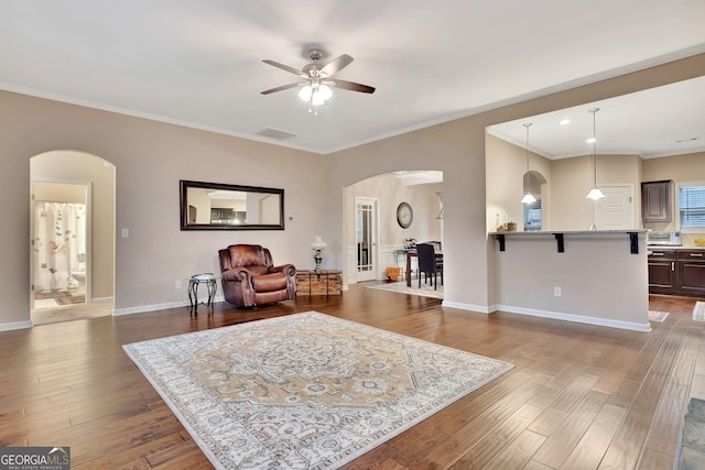 living room featuring ornamental molding, dark wood-type flooring, and ceiling fan