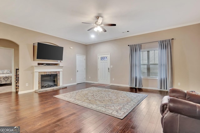 living room with hardwood / wood-style floors, a fireplace, ornamental molding, and ceiling fan