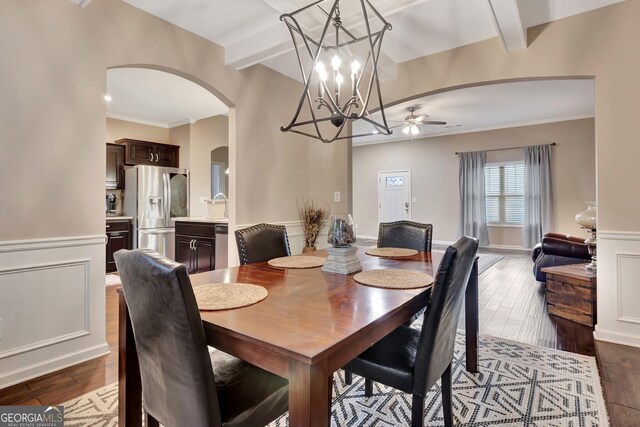 dining space featuring beamed ceiling, wood-type flooring, crown molding, and ceiling fan