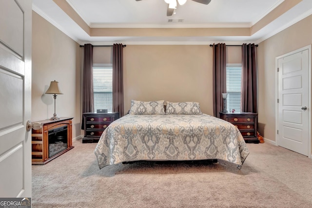 bedroom with a tray ceiling, ornamental molding, light colored carpet, and ceiling fan