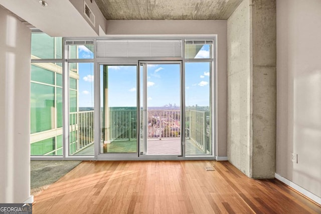 doorway to outside with hardwood / wood-style flooring, a wealth of natural light, and a wall of windows