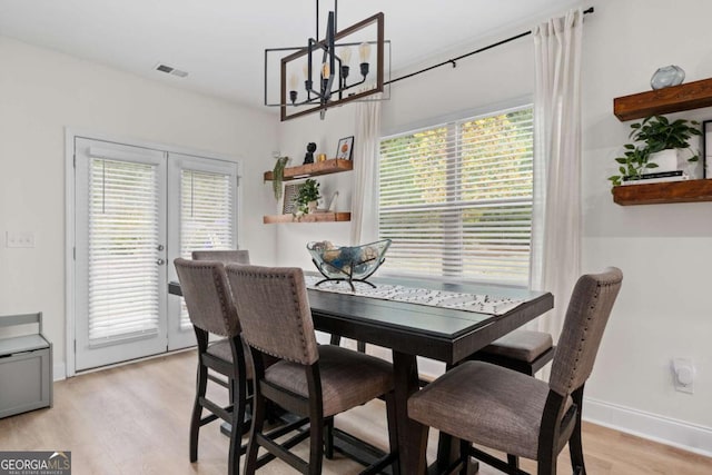 dining room featuring light hardwood / wood-style flooring, french doors, and a chandelier