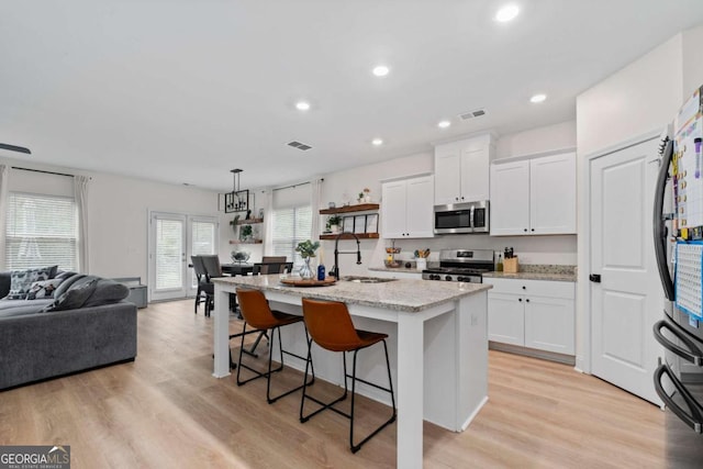 kitchen with stainless steel appliances, hanging light fixtures, a kitchen island with sink, and sink