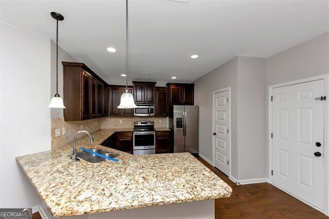 kitchen with sink, kitchen peninsula, pendant lighting, stainless steel appliances, and backsplash