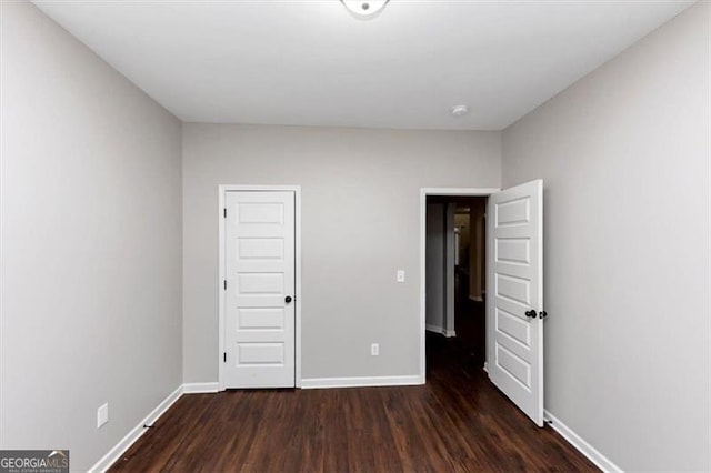 unfurnished bedroom with dark hardwood / wood-style floors and a closet