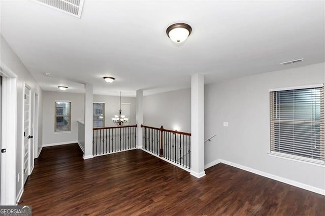 spare room with dark hardwood / wood-style flooring and a notable chandelier