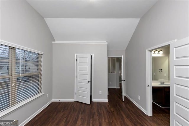 unfurnished bedroom featuring lofted ceiling, ensuite bath, and dark wood-type flooring