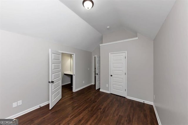 unfurnished bedroom featuring dark hardwood / wood-style flooring, vaulted ceiling, and a closet