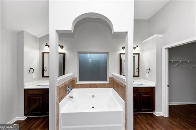 bathroom with wood-type flooring, a bathtub, and vanity