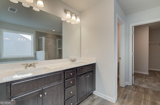 bathroom featuring a shower with door, vanity, hardwood / wood-style floors, and toilet