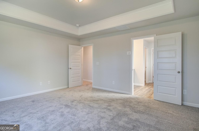 unfurnished room featuring light colored carpet, ornamental molding, and a raised ceiling