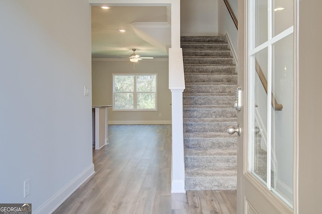 stairway with wood-type flooring, ornamental molding, and ceiling fan