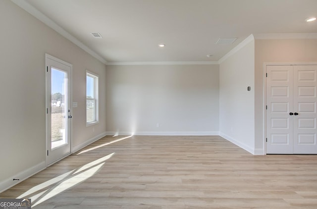 spare room featuring crown molding, a healthy amount of sunlight, and light hardwood / wood-style flooring