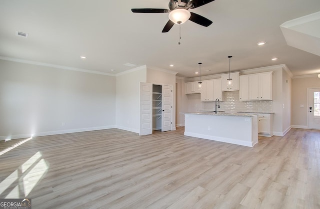 kitchen with white cabinetry, crown molding, light wood-type flooring, and a center island with sink