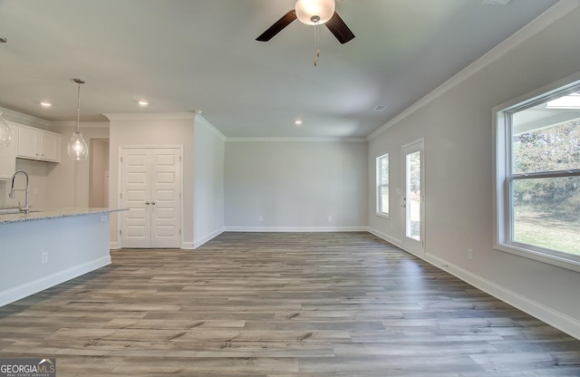 unfurnished living room featuring crown molding, sink, ceiling fan, and light hardwood / wood-style flooring